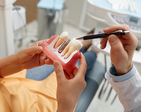 dentist pointing to dental implant model