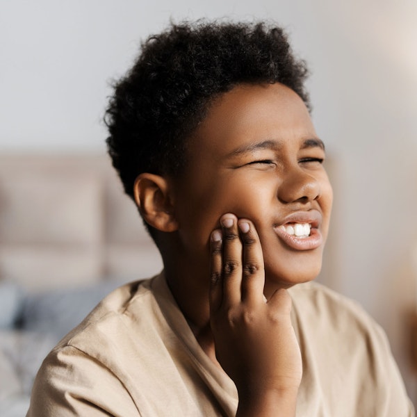 Young boy holding jaw in pain