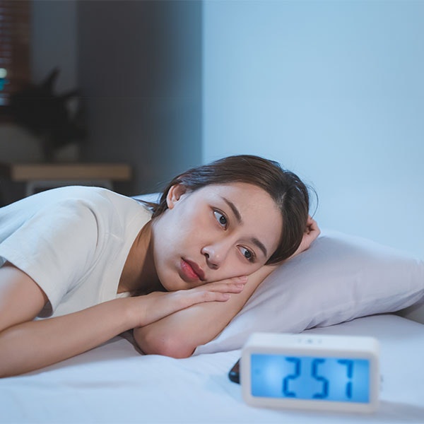 Woman lying awake in bed at 2:57 in the morning