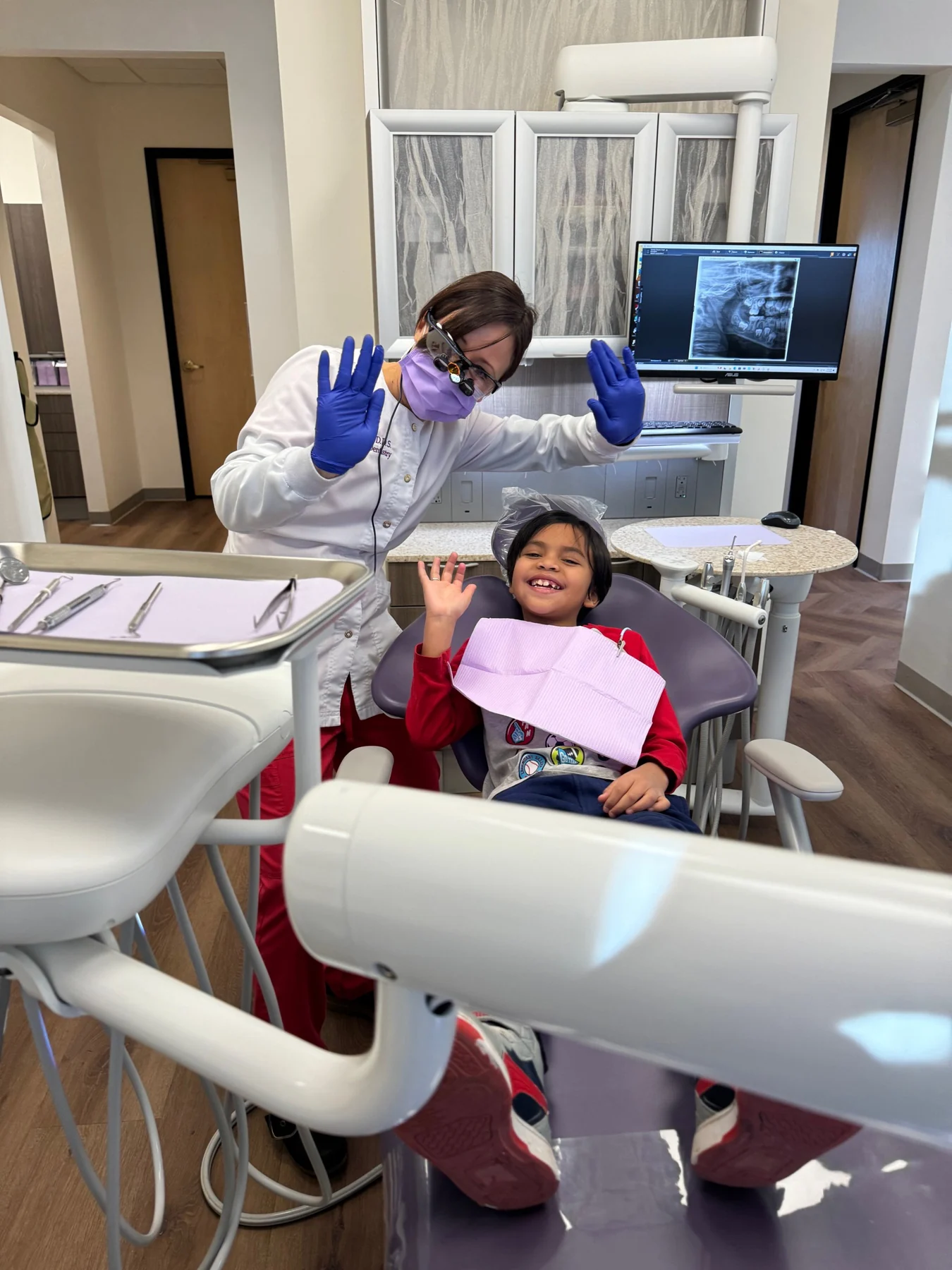 Dr. Adams and a smiling young patient in a Peak Family Dentistry treatment room
